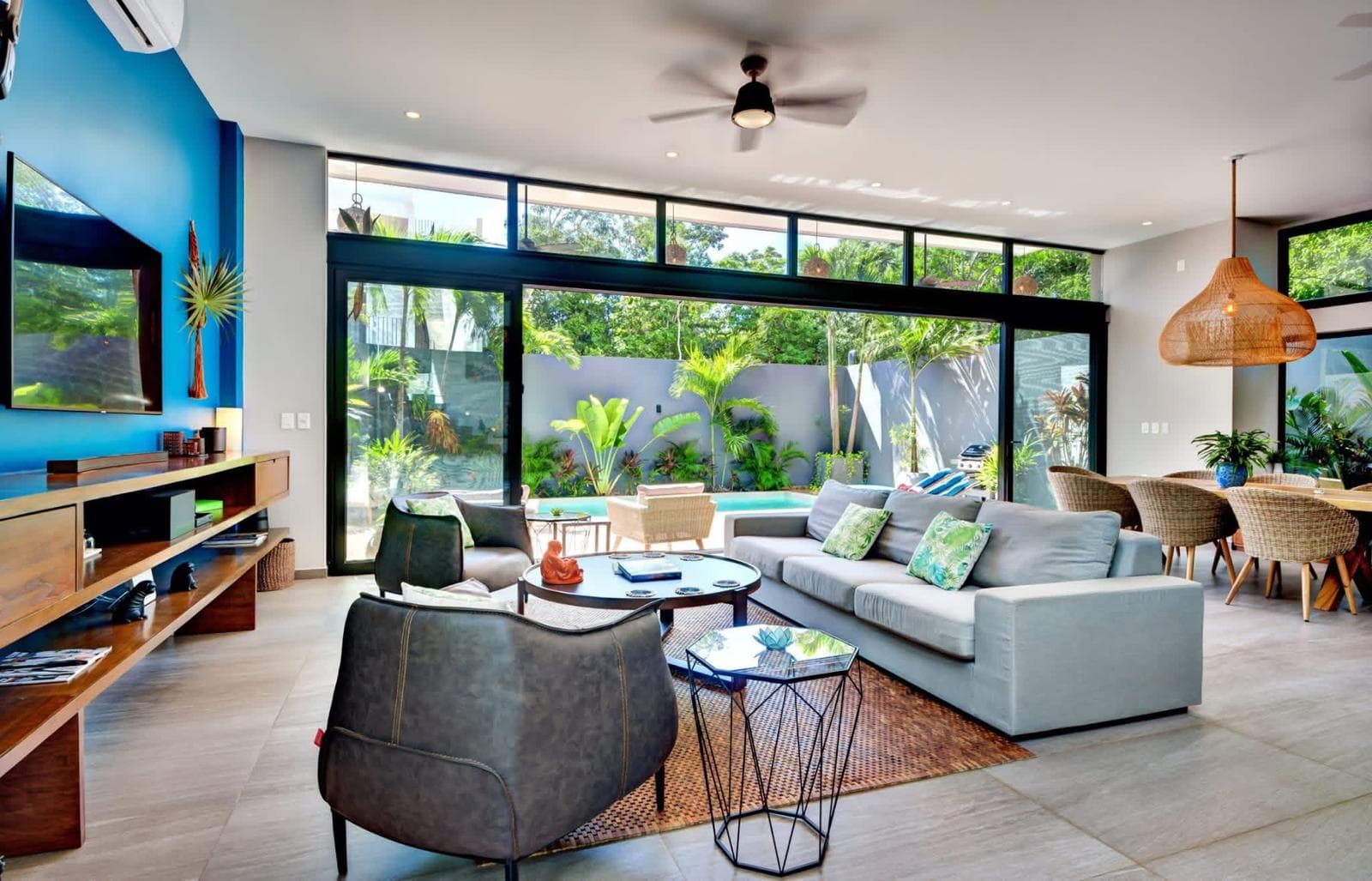 Living room with a grey sectional, leather chair and rattan pendant