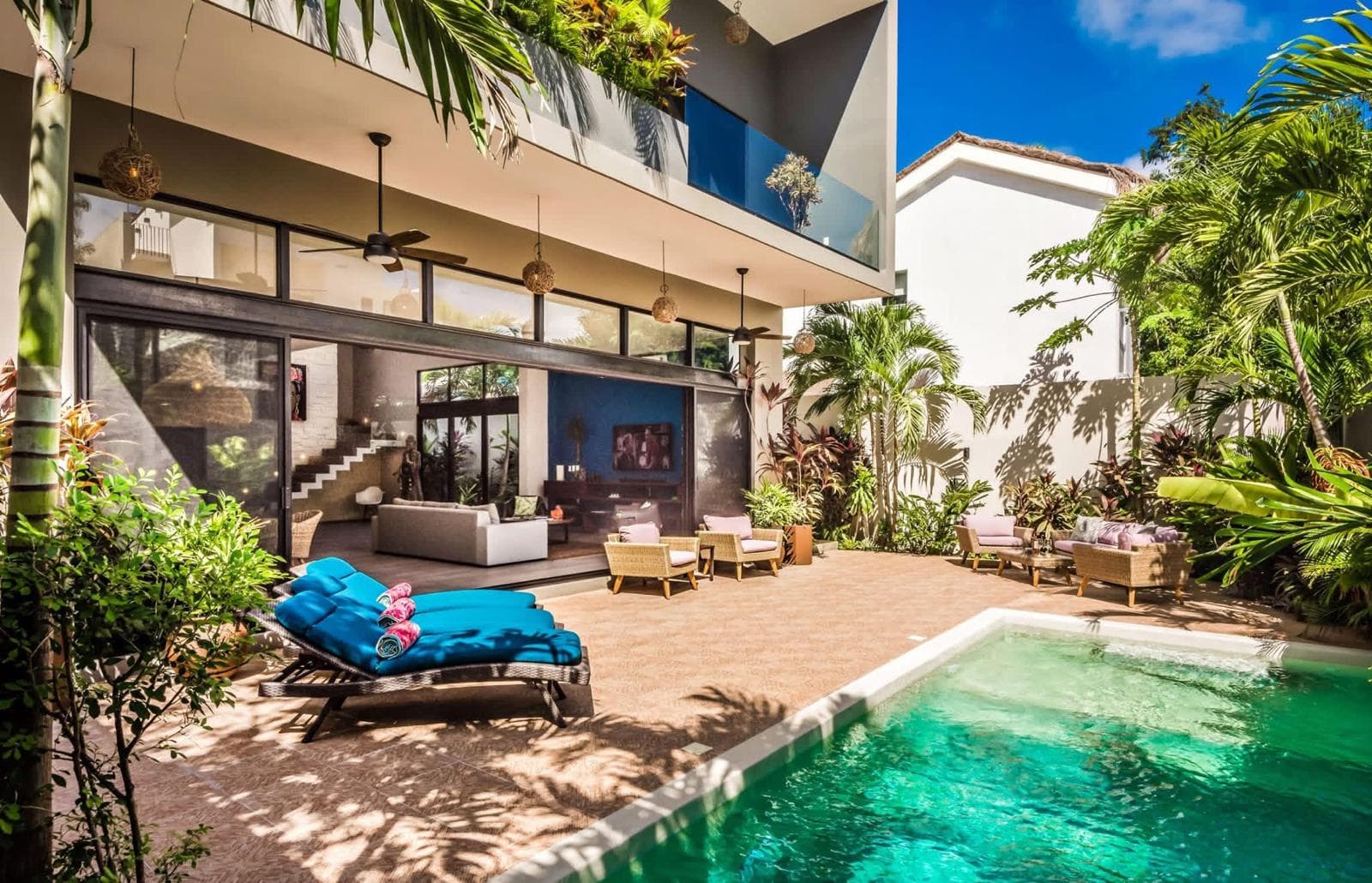 Pool with blue loungers looking into an open living room