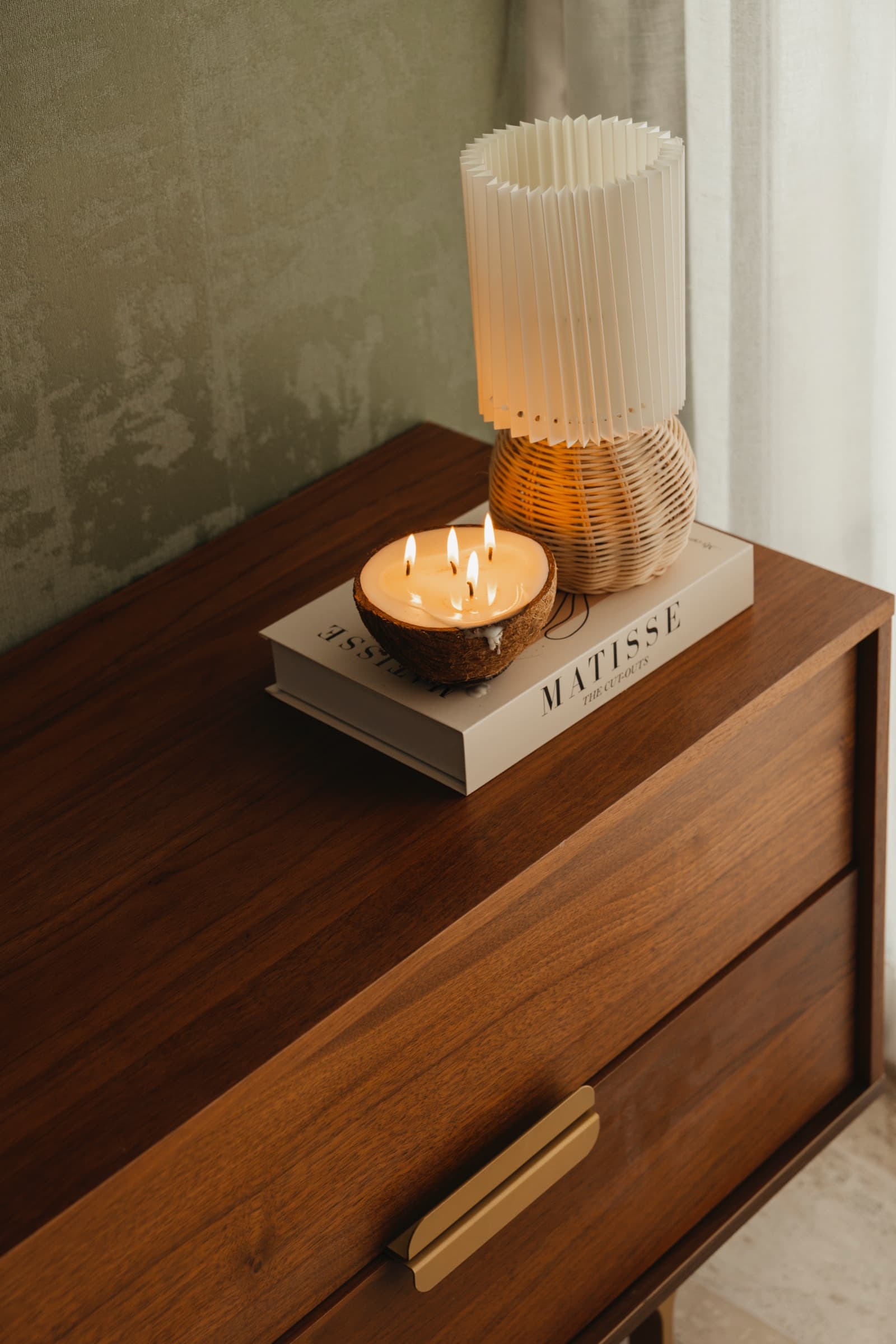 Walnut dresser styled with a candle, books and a ribbed lamp
