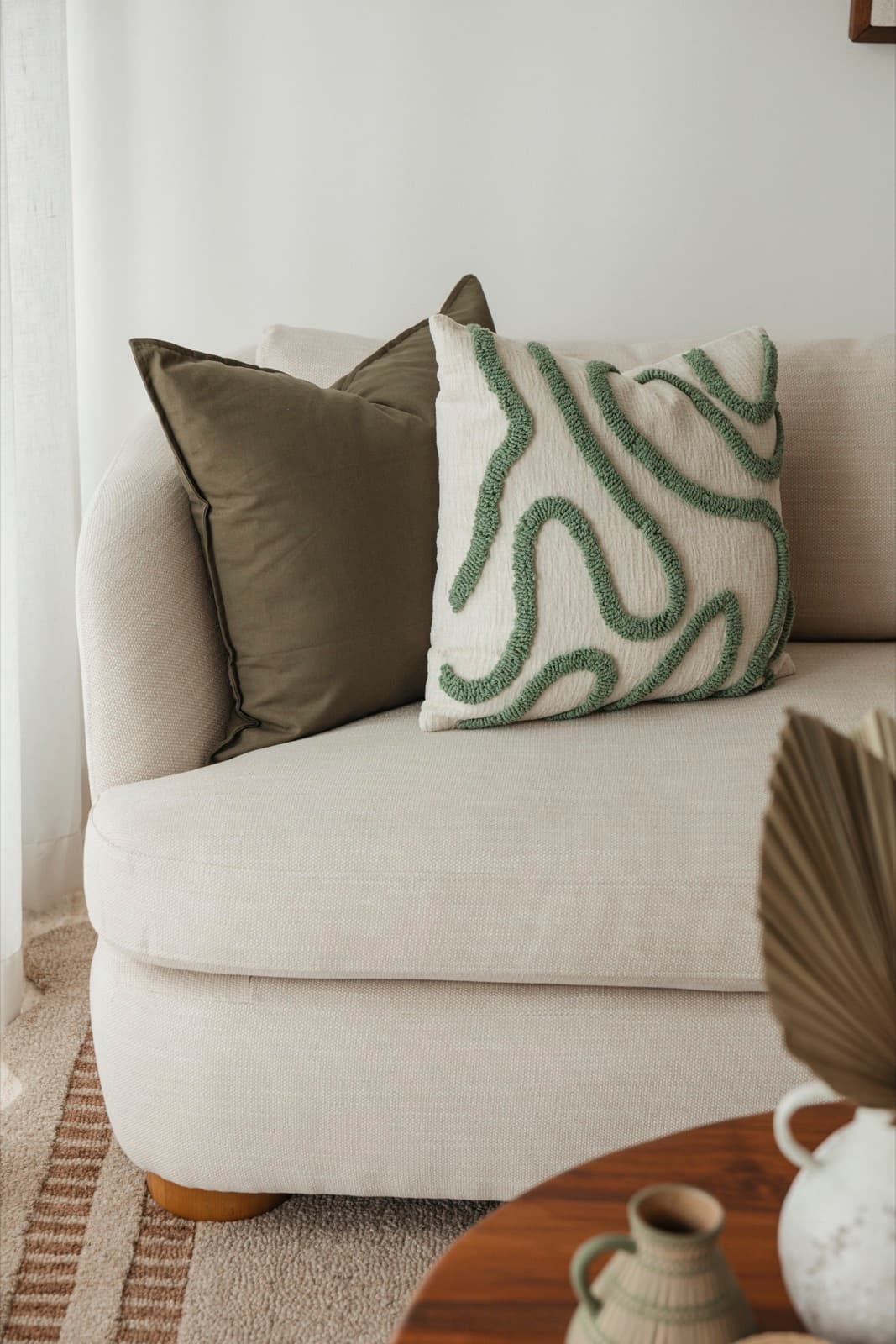 Cream curved sofa with olive and sage cushions
