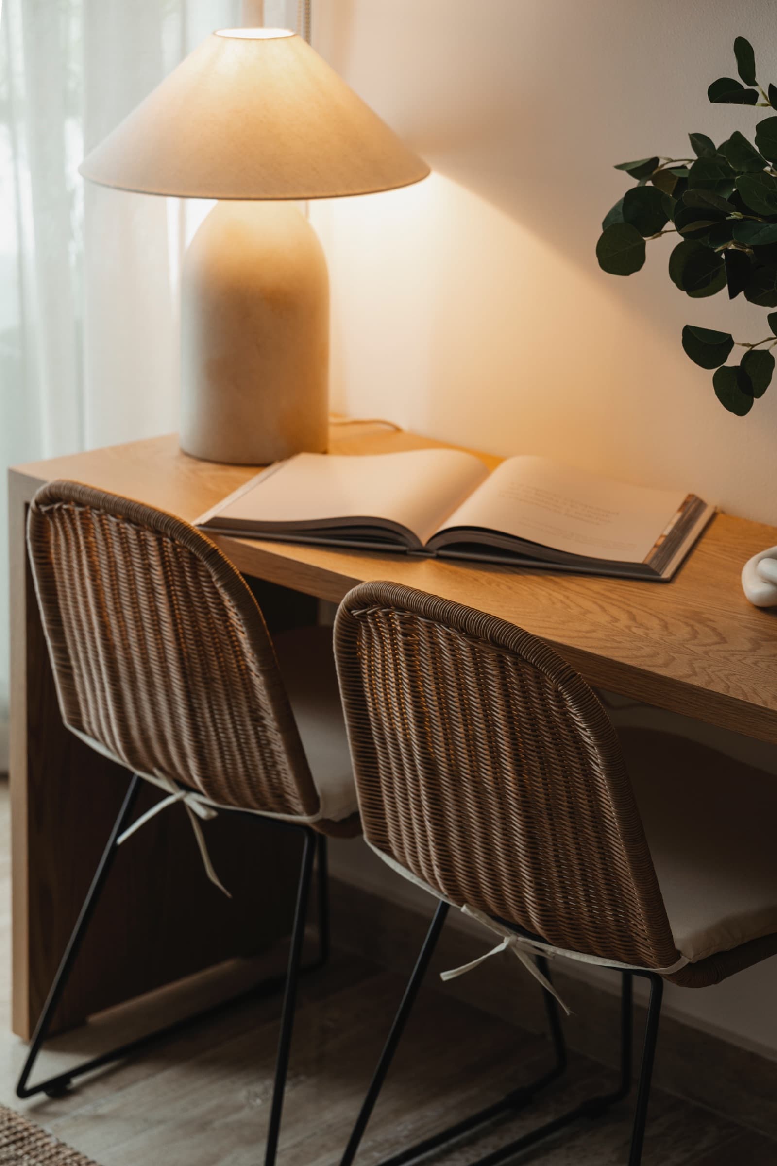 Desk corner with a ceramic lamp and two rattan chairs