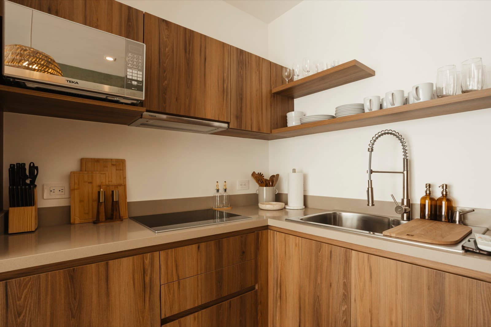 Walnut kitchen with open shelves, glassware and a gooseneck tap