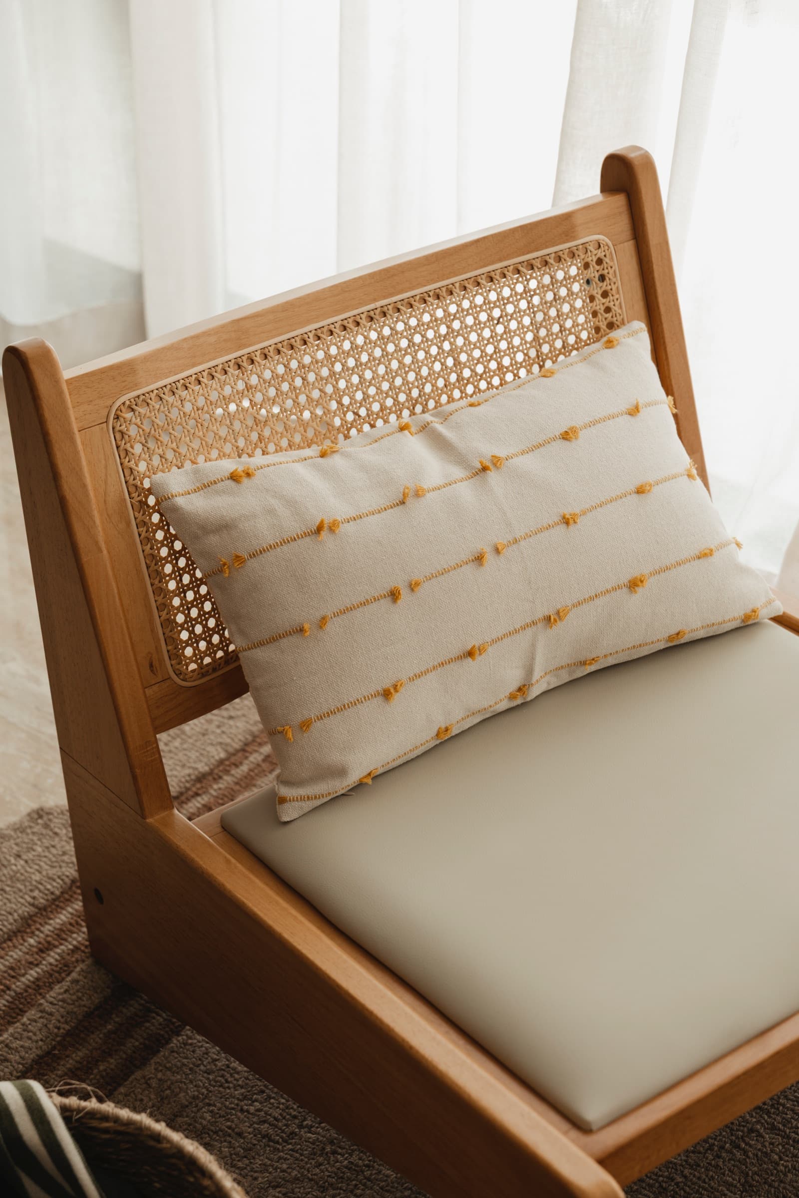 Cane lounge chair with a striped lumbar cushion
