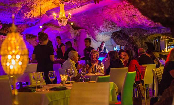 Alux restaurant dining room inside a lit limestone cave in Playa del Carmen