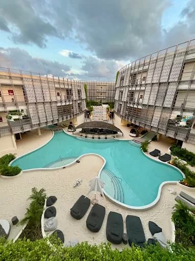Vista aérea de la alberca central de Artia Condos con arena blanca en Aldea Zama