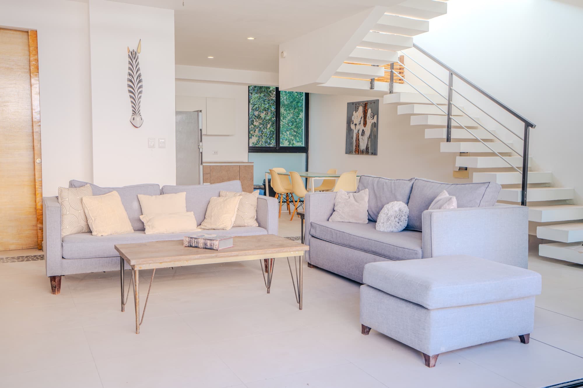 Open plan lounge with two sofas beside the floating staircase